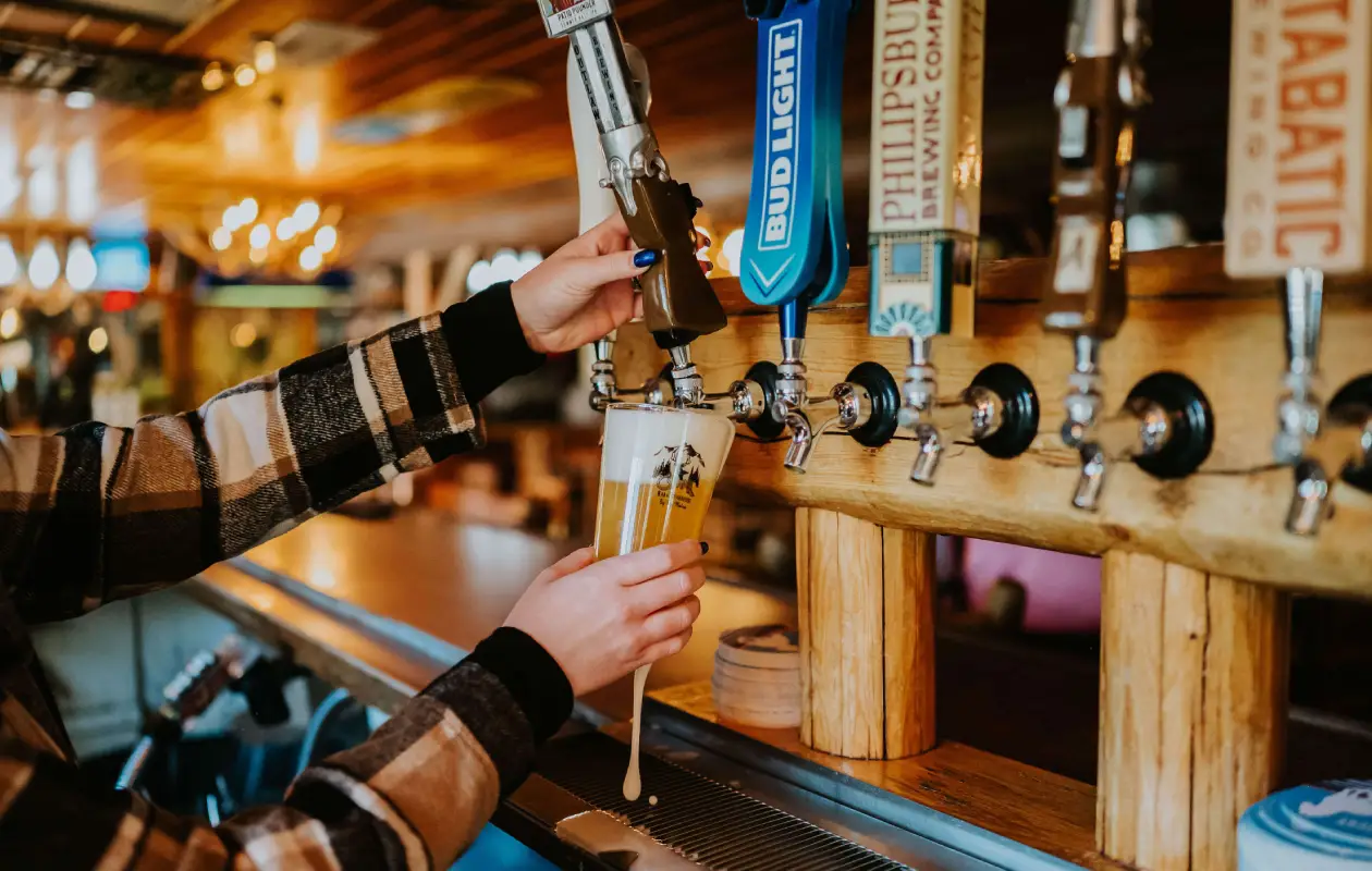 A woman pours a beer from the tap inside the Corral Bar and Steakhouse in Gallatin Gateway, MT.
