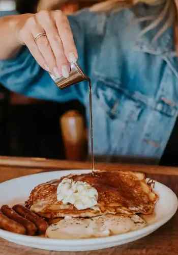A woman pours syrup over a stack of pancakes for breakfast at the Corral Bar and Steakhouse.