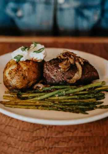A woman prepares to eat a dinner of sirloin steak, mashed potatoes, and asparagus at Corral Bar and Steakhouse.